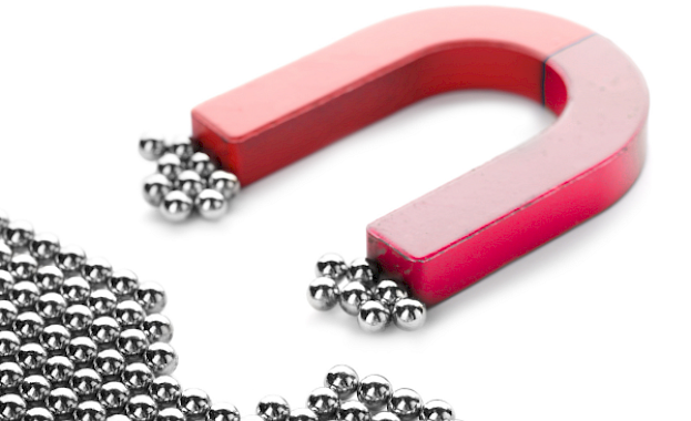 A red horseshoe magnet attracting metal beads